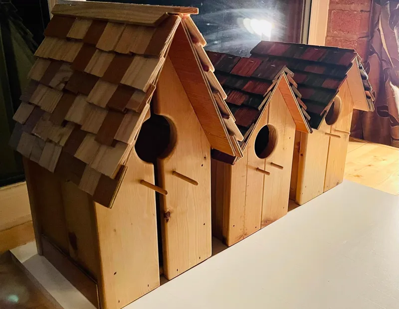 Row of handcrafted bird houses with individually shingled roofs