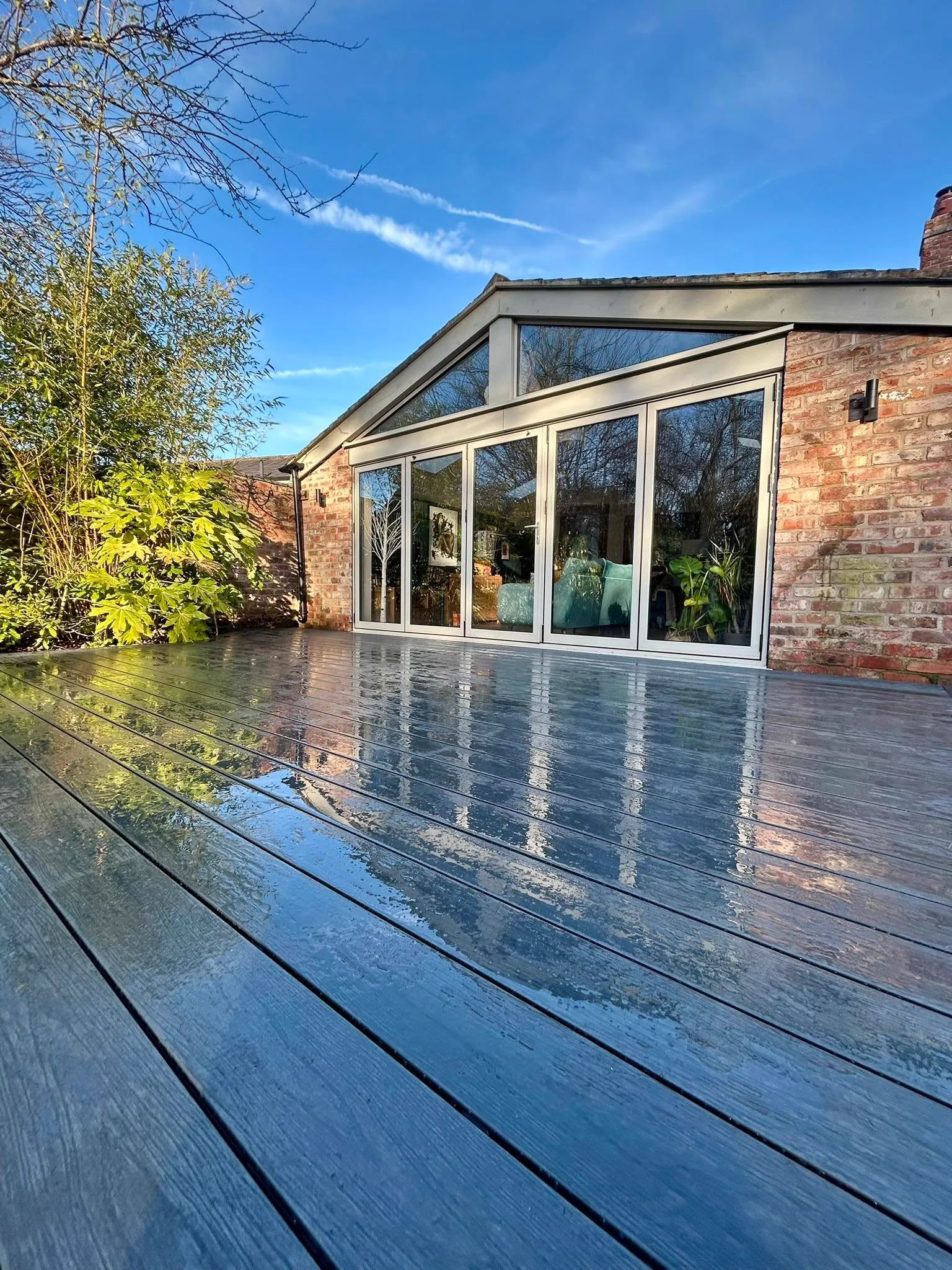 Grey composite decking flowing from bifold doors after rain