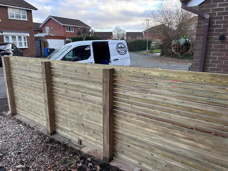 New horizontal slatted fence with company van in the background