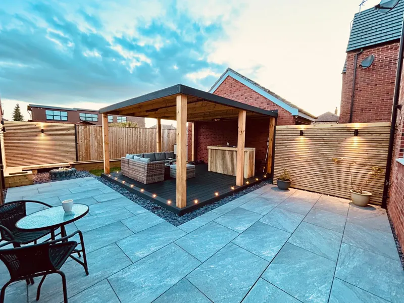 Timber gazebo with outdoor bar, porcelain patio and lit slatted fencing at dusk