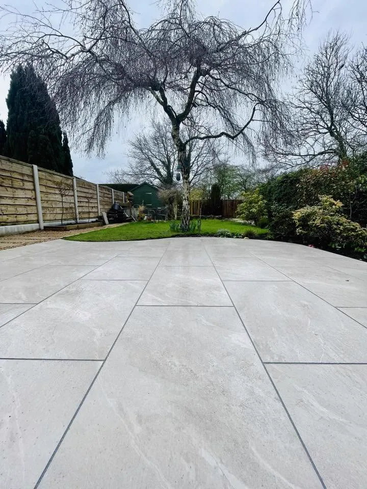 Large-format cream porcelain patio flowing towards a mature garden
