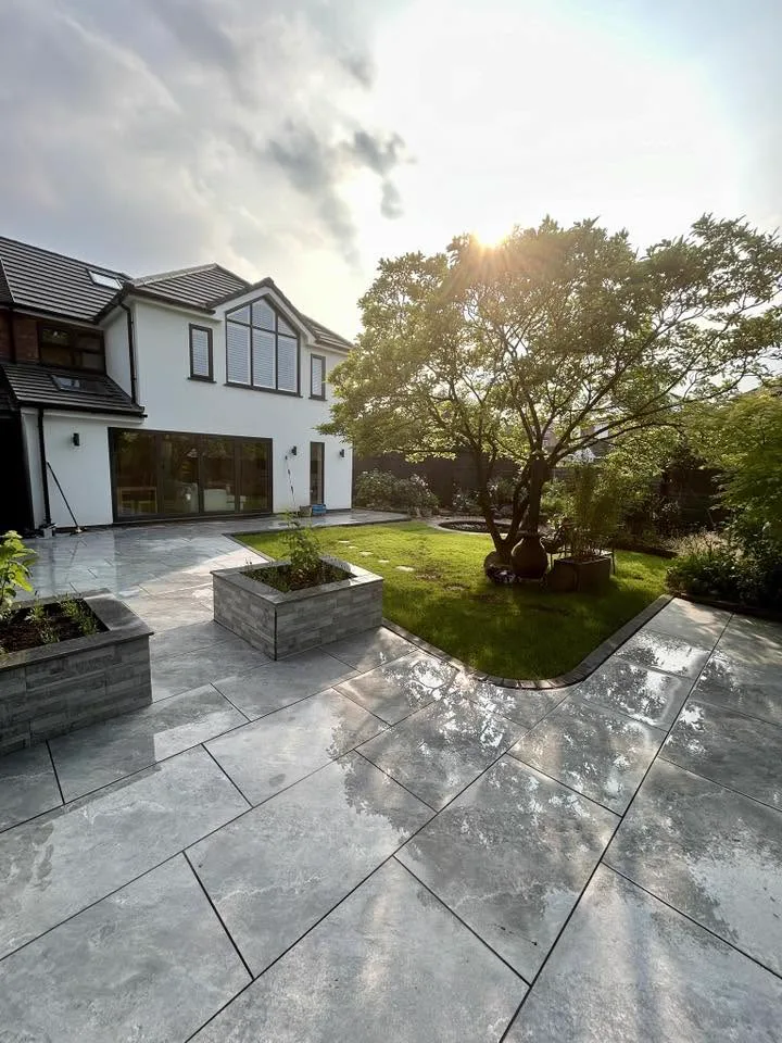 Porcelain paving and raised stone planters wrapping a detached Cheshire home