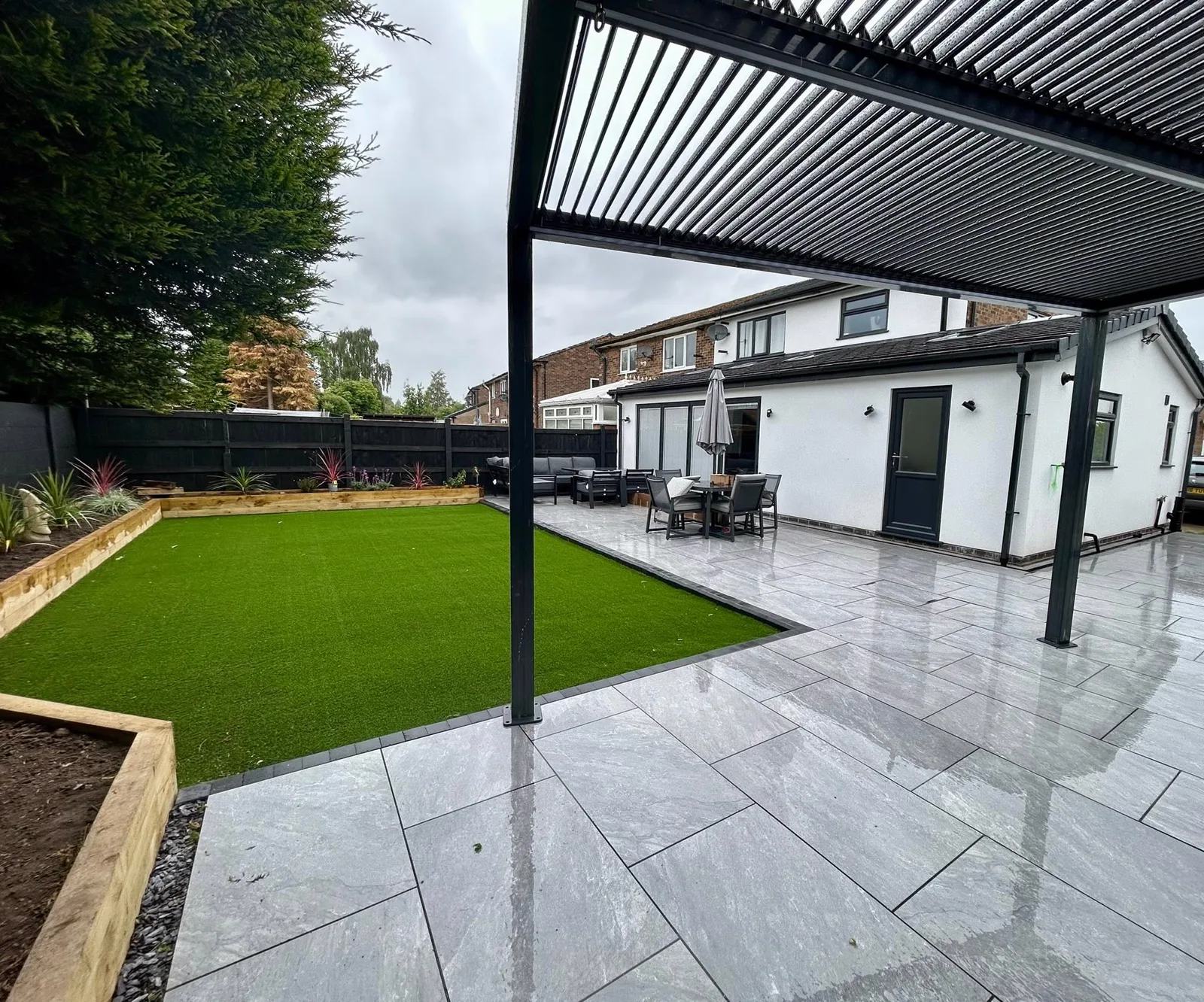 Louvred pergola over porcelain patio with artificial lawn and sleeper planting beds